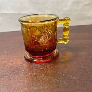 M-Degenhart Stork and‎ Peacock amber mug 2.5 inches